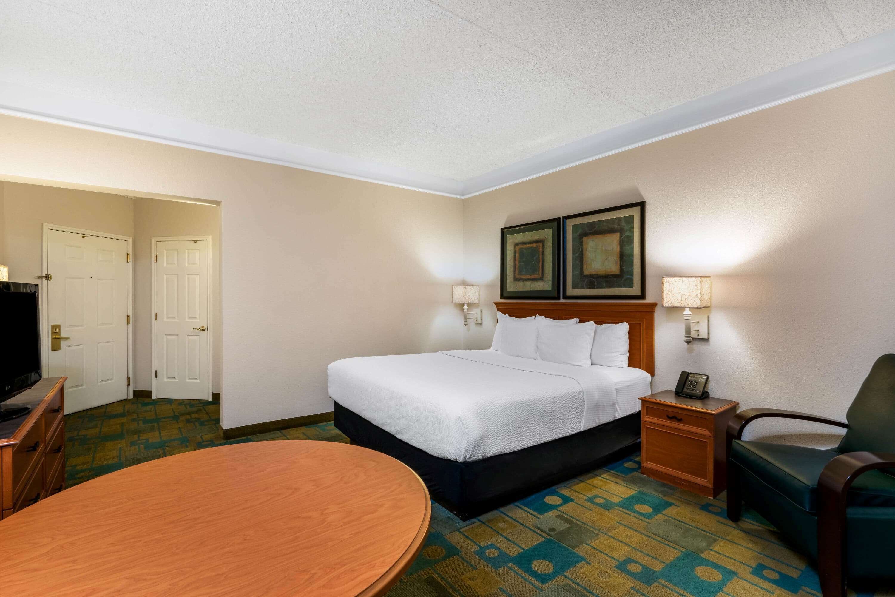 Une chambre d’hôtel comprenant un lit, des lampes de chevet, un bureau, une chaise et un téléviseur.