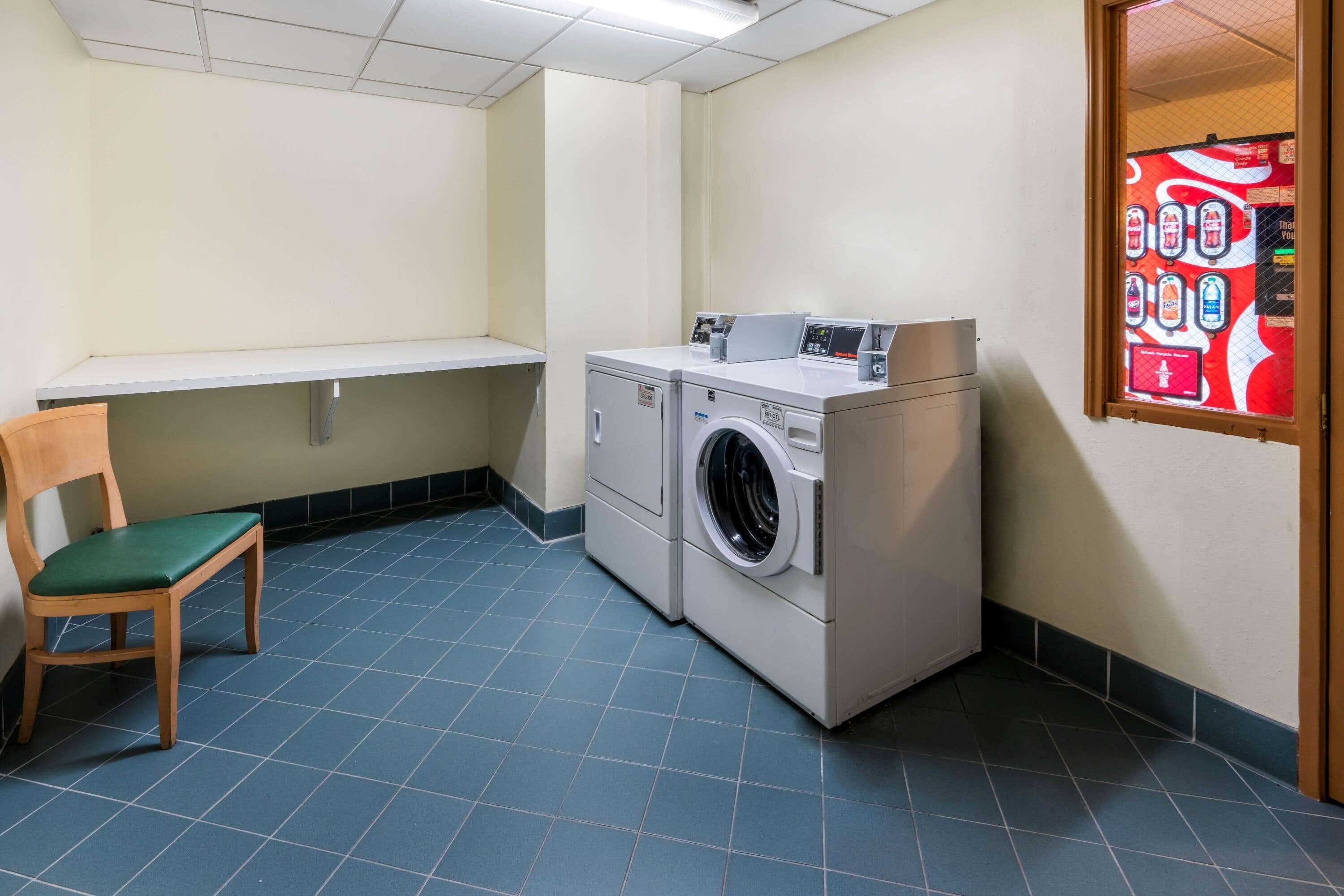 A laundry room with a washing machine, a chair, and a shelf.