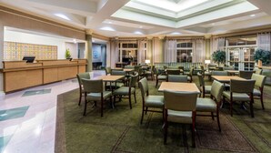 Eine großzügige Hotelhalle mit Empfangstresen, mehreren Sitzbereichen und einer hohen Decke mit Oberlichtern.