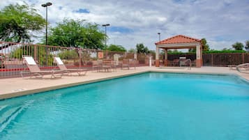 Una piscina al aire libre, sillones reclinables de piscina