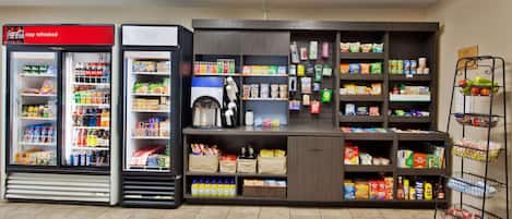 A self-service beverage station with Coca-Cola and other drinks, a coffee machine, and a variety of snacks and groceries.