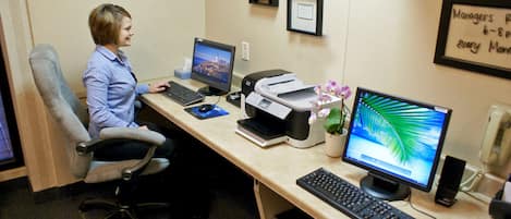 A cubicle with a computer, printer, and a desk lamp.