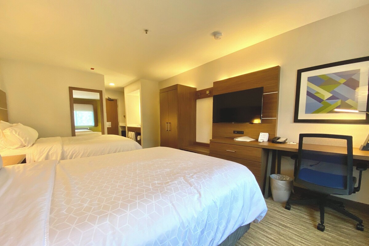 Une chambre d’hôtel avec deux lits, un bureau, une chaise, une télévision et une salle de bain.