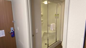 Un baño con ducha acristalada, una toalla colgada en la pared y una puerta con el letrero 'Hang On'.