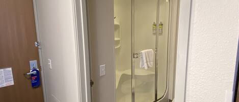 Un baño con ducha vidriada, una toalla colgada en la pared y una puerta con un letrero que dice 'Hang On'.