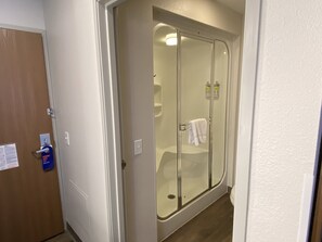 Un baño con ducha vidriada, una toalla colgada en la pared y una puerta con un letrero que dice 'Hang On'.