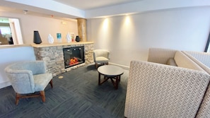 Una sala de estar con chimenea de piedra, dos sillones, una mesa redonda y un sofá.