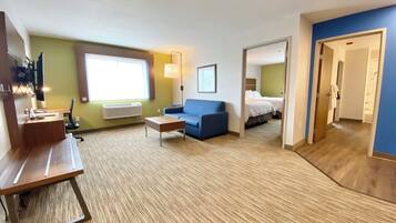 A hotel room with a sofa, a desk, a bed, and a bathroom visible through an open door.