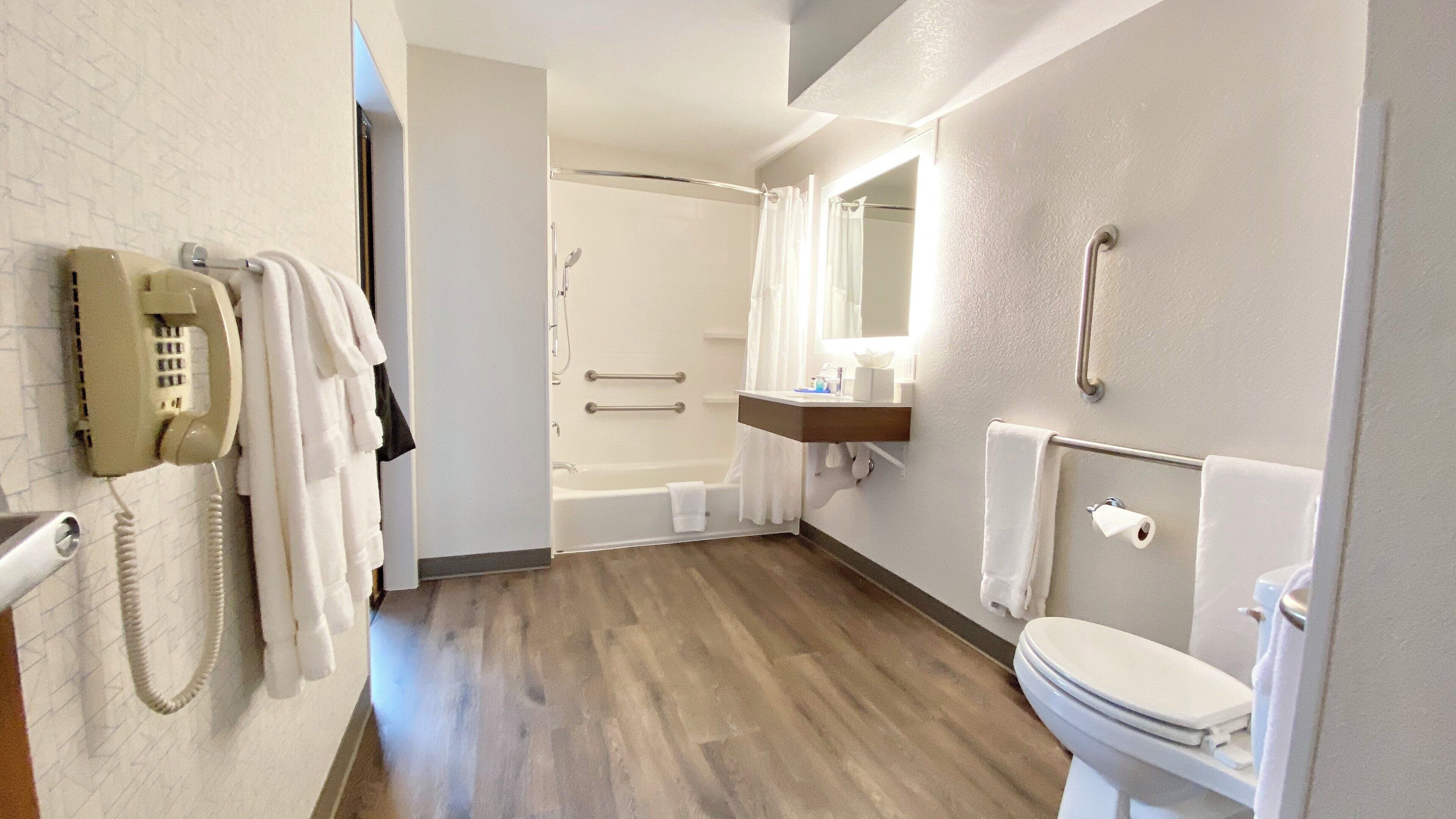 Un baño de hotel con bañera, inodoro y teléfono.