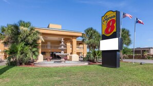A hotel with a prominent 'Super 8' sign, a fountain, and palm trees in the foreground.