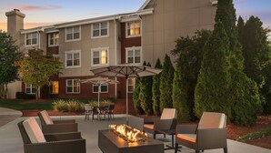 An outdoor patio with a fire pit, wicker furniture, and a view of a building with multiple windows. - Residence Inn by Marriott Gaithersburg Washingtonian Center (Gaithersburg)