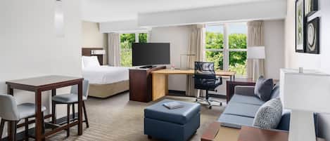 Una habitación de hotel con una cama, un escritorio con televisor, un sofá y una mesita.