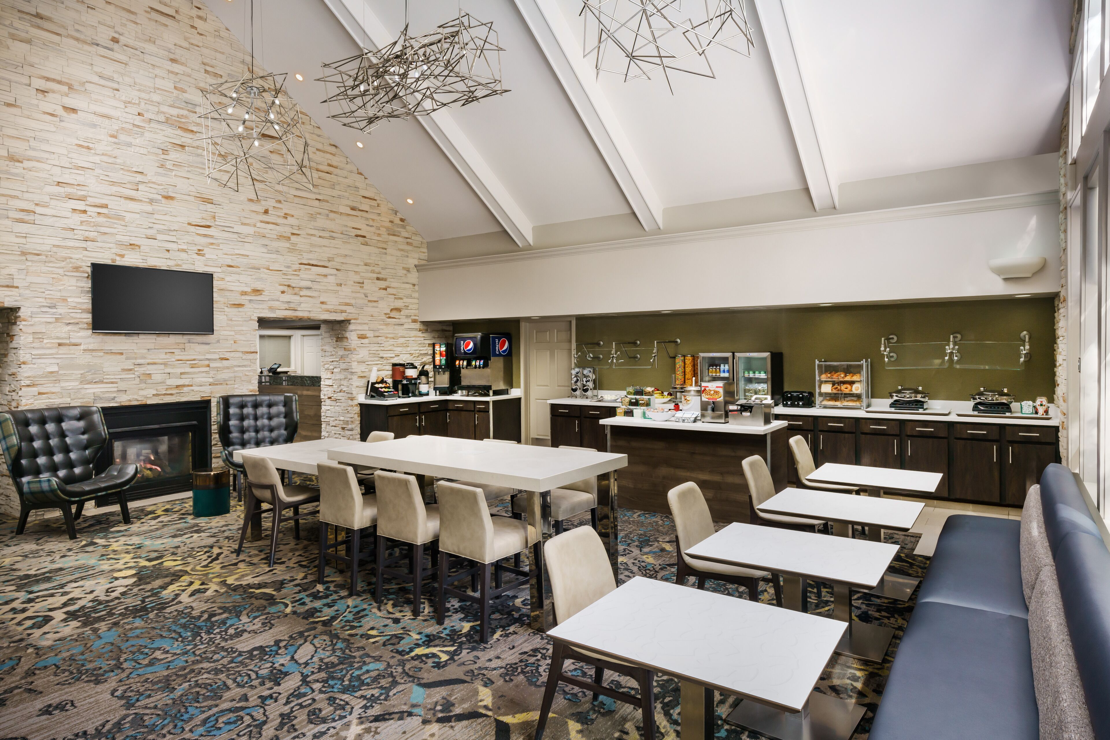 Um hall de hotel moderno com lareira, área de estar e bar.