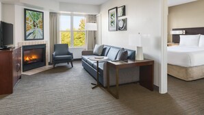 A hotel room with a fireplace, a sofa, a bed, a TV, and artwork on the walls. - Residence Inn by Marriott Gaithersburg Washingtonian Center (Gaithersburg)