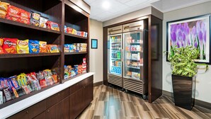 Een ruimte voor snacks en drankjes met planken vol chips en een gekoelde vitrine.