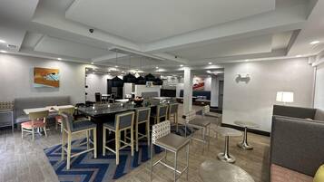 A modern hotel lobby with a central dining area, seating arrangements, and a reception desk.