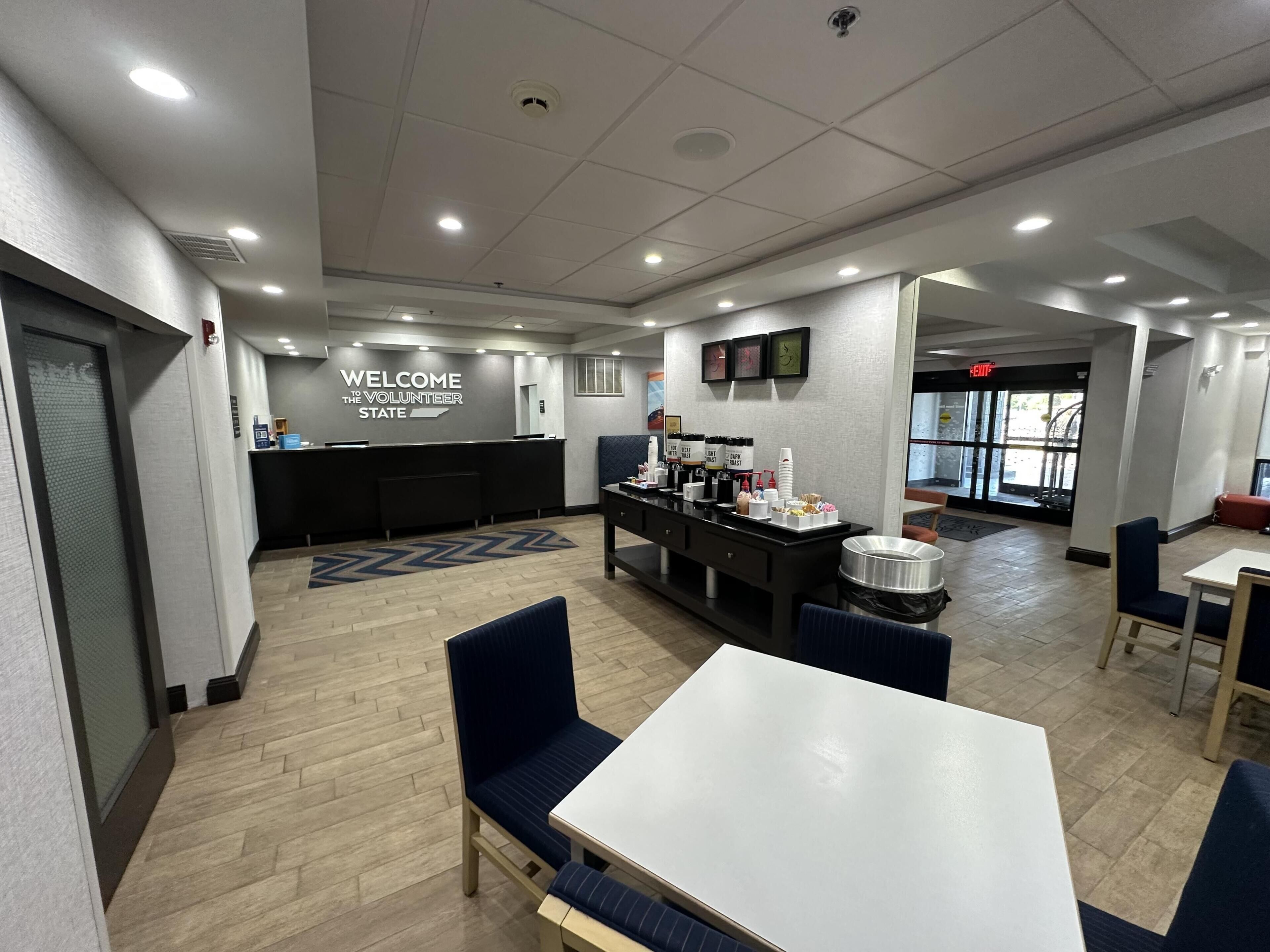 A modern reception area with a 'Welcome to the Volunteer State' sign, a counter, and a buffet with various food items.