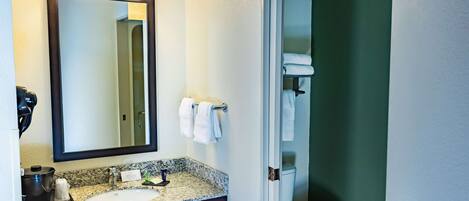A bathroom with a sink, mirror, towel rack, and toilet.
