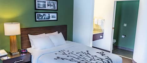 A hotel room with a bed, nightstand, lamp, and two framed pictures on the wall.
