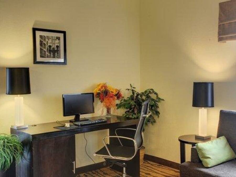 A hotel reception area with a desk, computer, chair, and a couch.