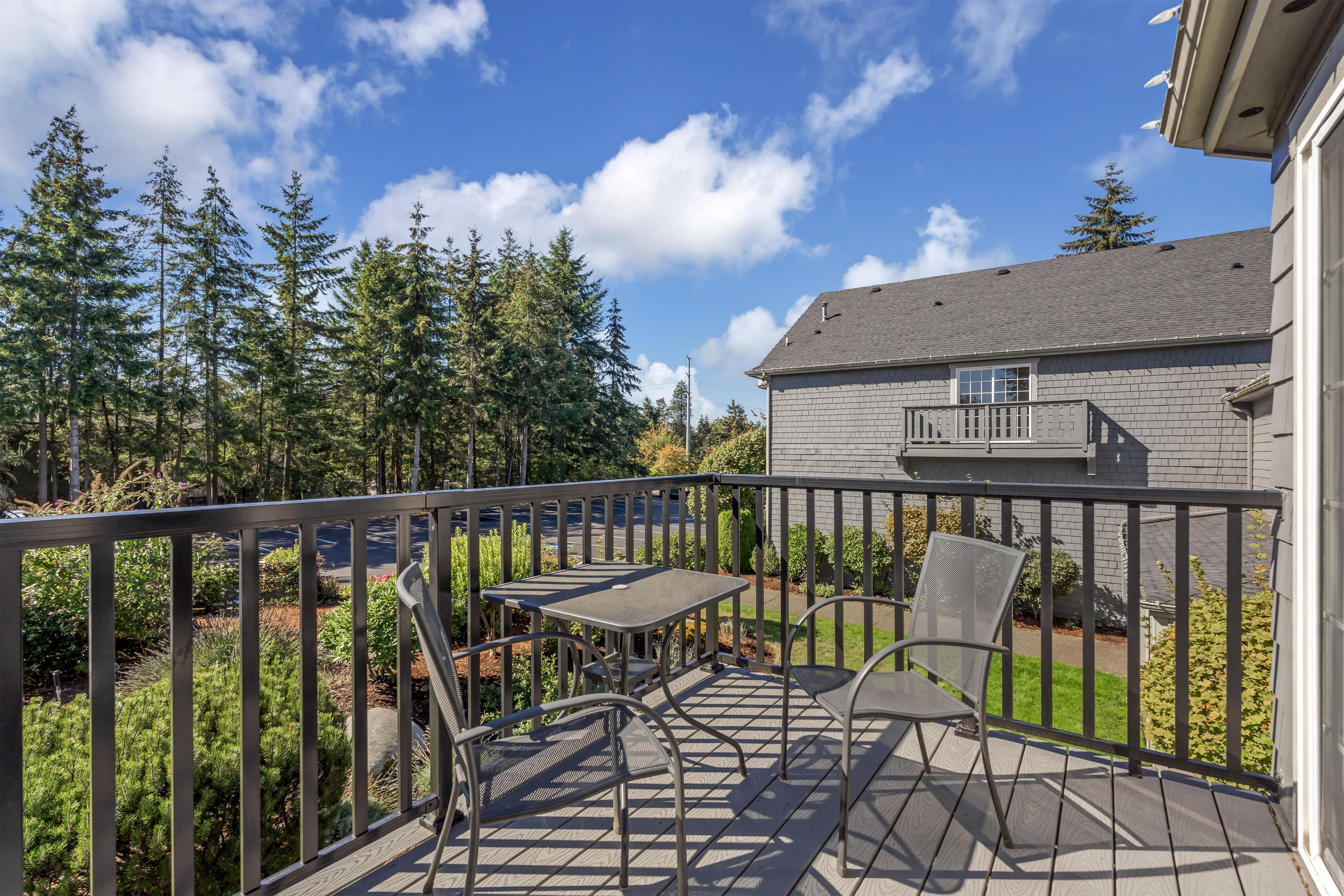 A deck with metal furniture and a view of a forest.