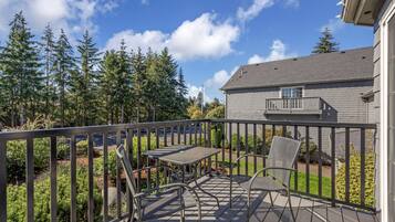 A deck with metal furniture and a view of a forest.