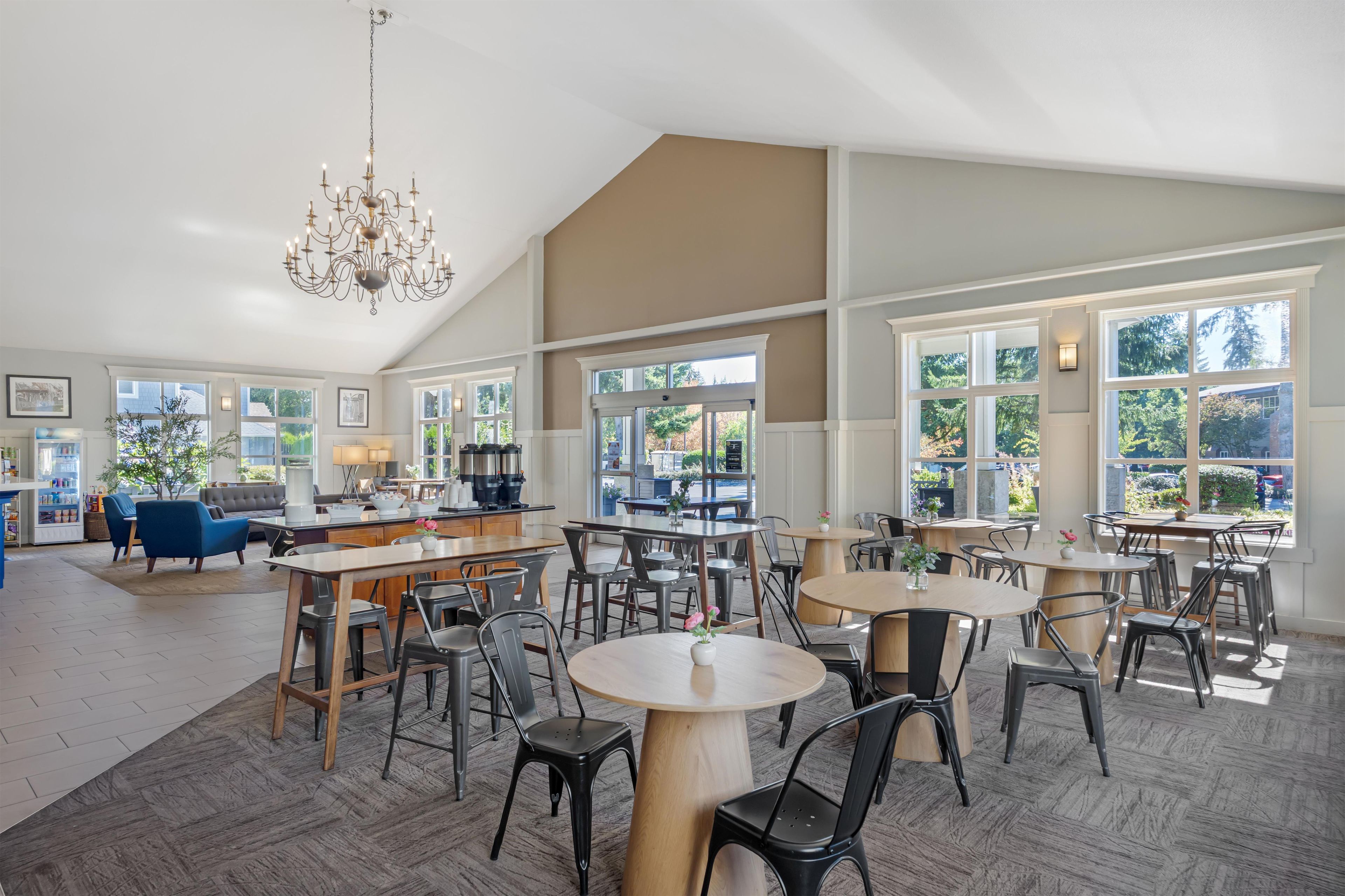 A spacious dining area with high ceilings and large windows, featuring a chandelier and modern furniture.