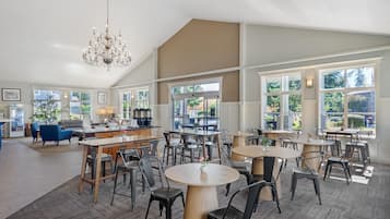 A spacious dining area with high ceilings and large windows, featuring a chandelier and modern furniture.