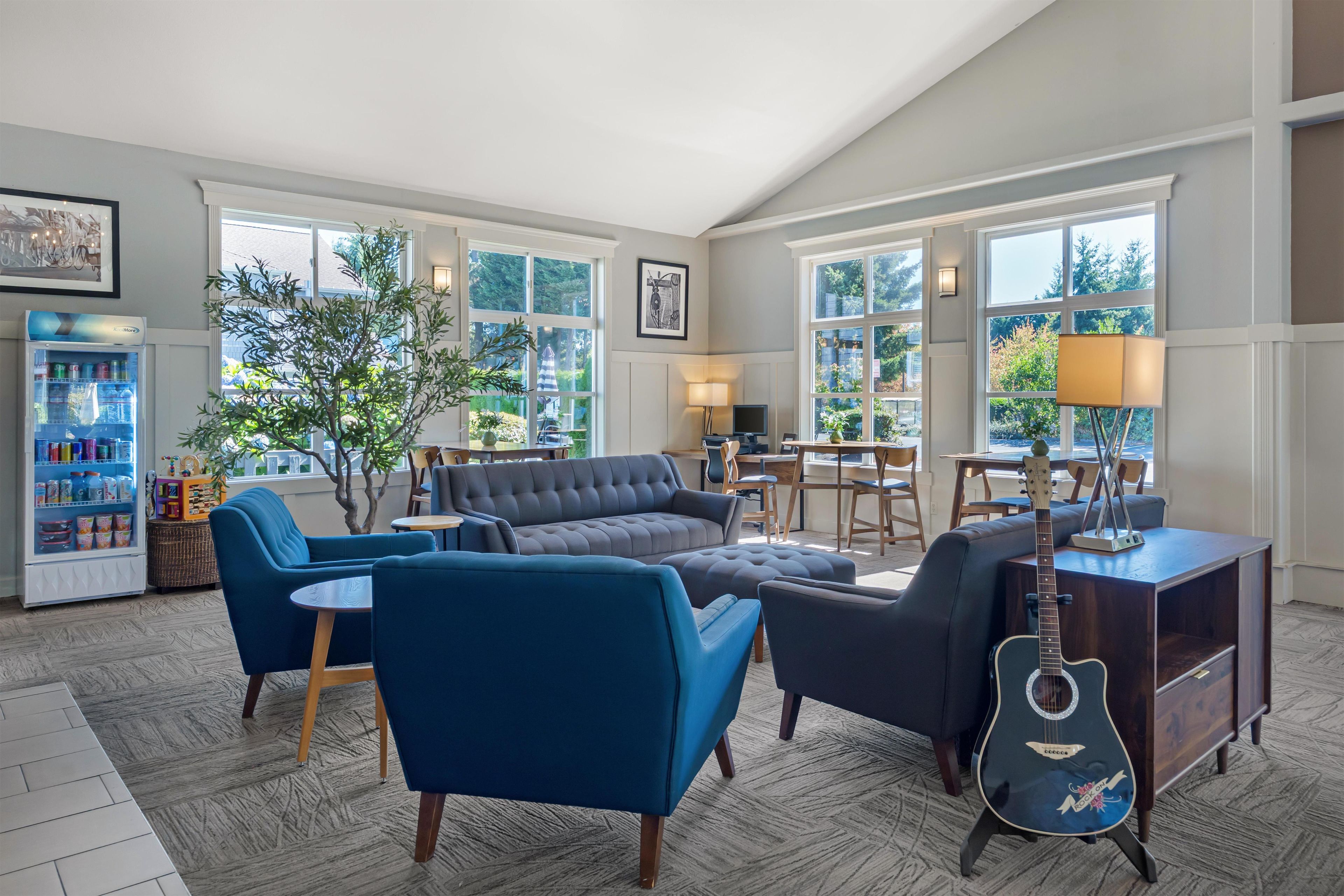 A spacious lounge area with a sofa set, a dining table, and a guitar.