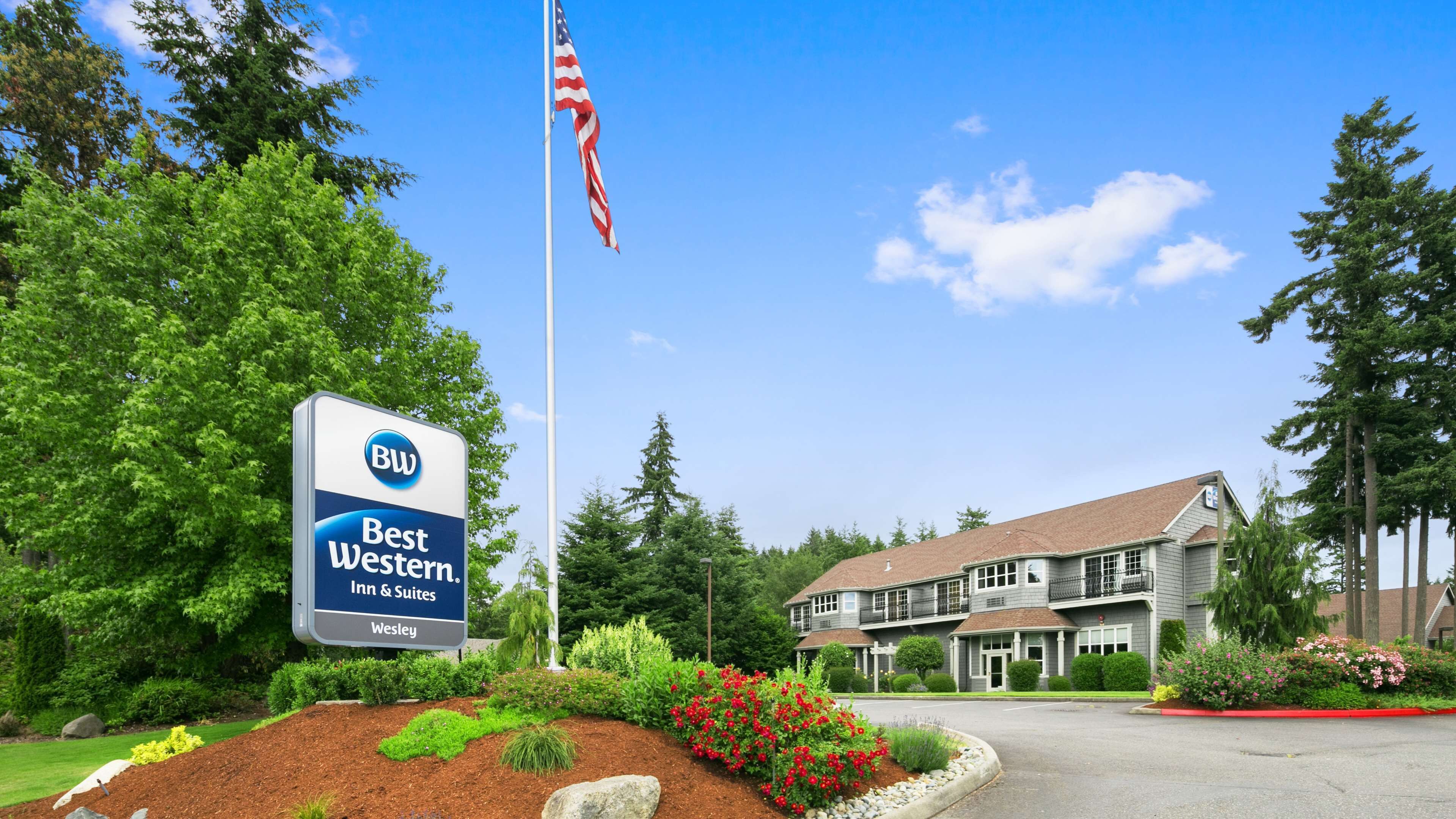 Letrero de Best Western Inn & Suites, una bandera y un edificio con fachada de ladrillo y varias ventanas.