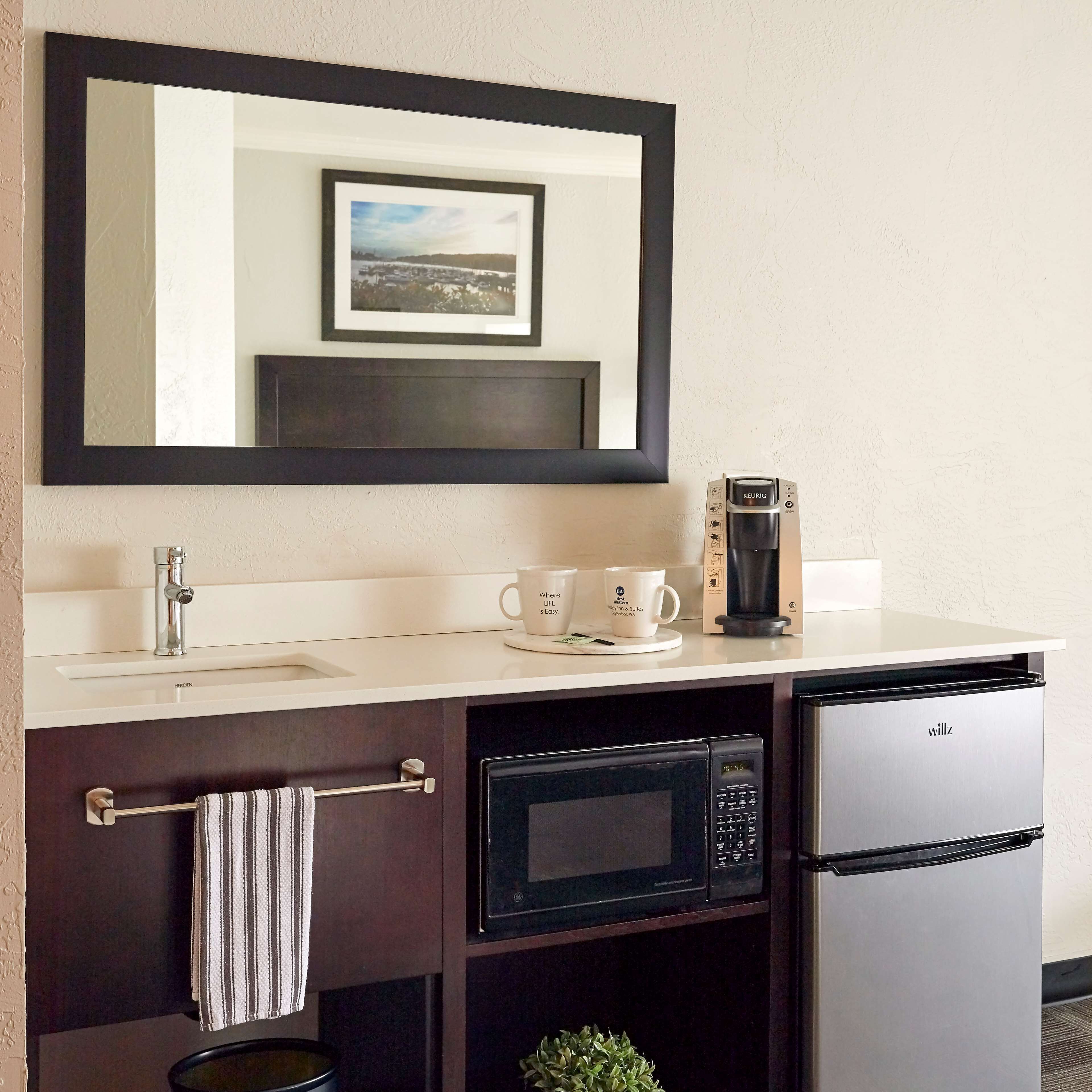 A compact kitchenette with a sink, microwave, coffee maker, and a refrigerator.
