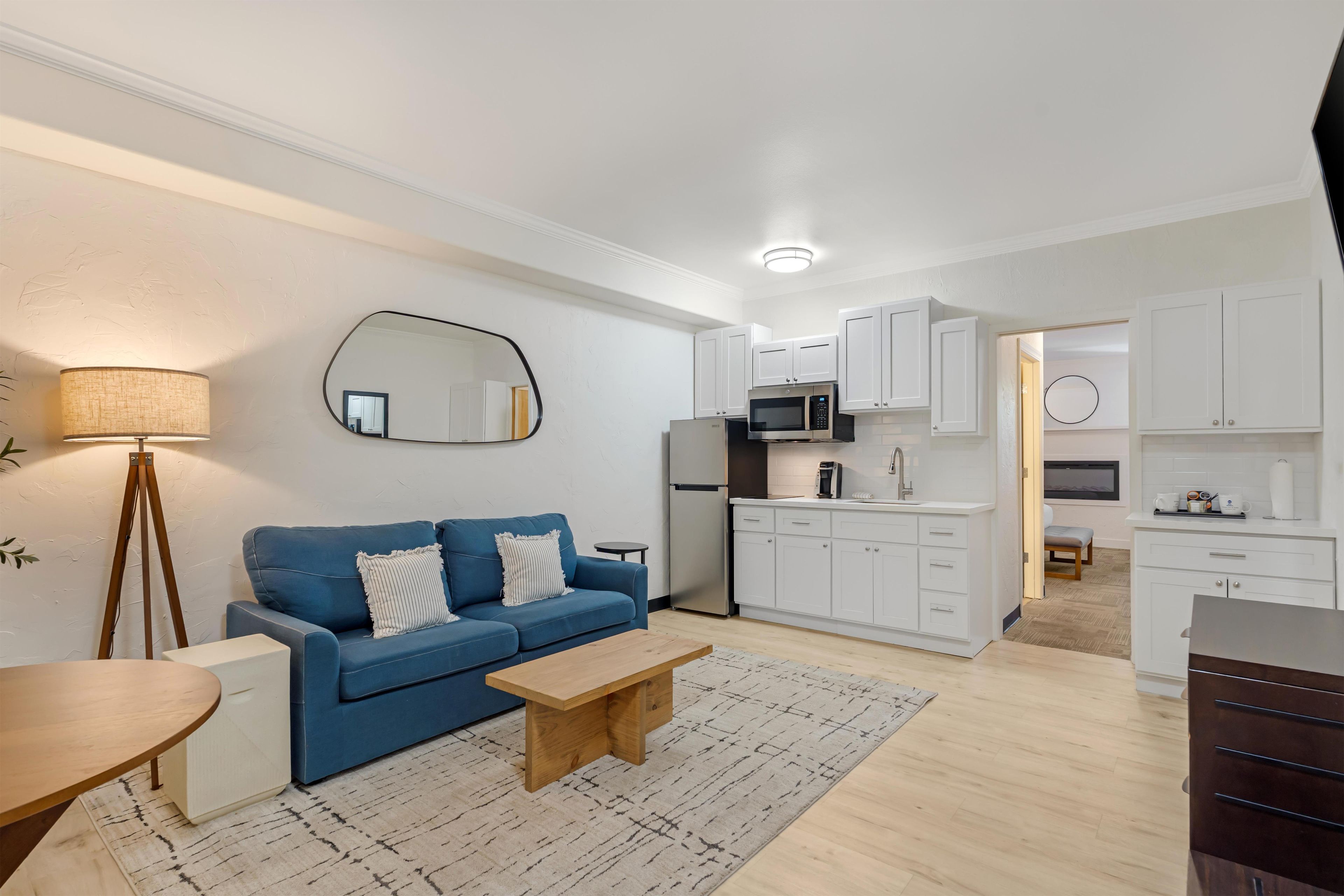 Uma sala de estar moderna com um sofá azul, uma mesa de centro de madeira e um abajur.