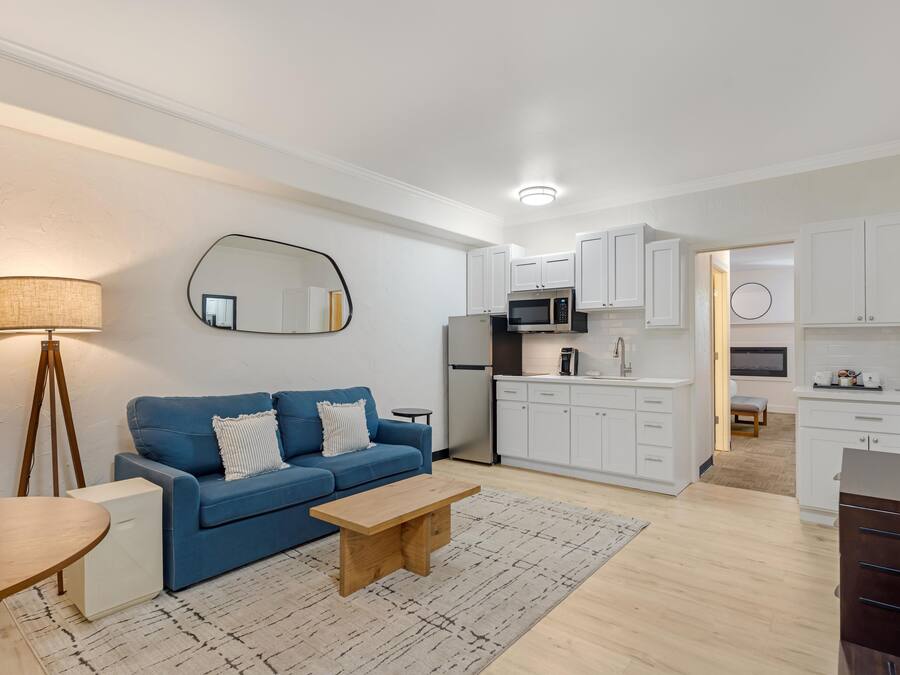 Uma sala de estar moderna com um sofá azul, uma mesa de centro de madeira e um abajur.