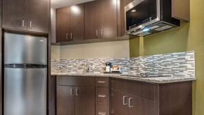 A kitchen with dark wooden cabinets, a stainless steel refrigerator, and a tiled backsplash.