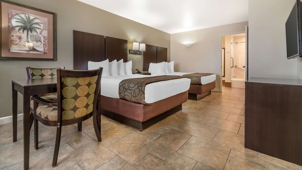 A hotel room with a large bed, a desk, a chair, and a television.