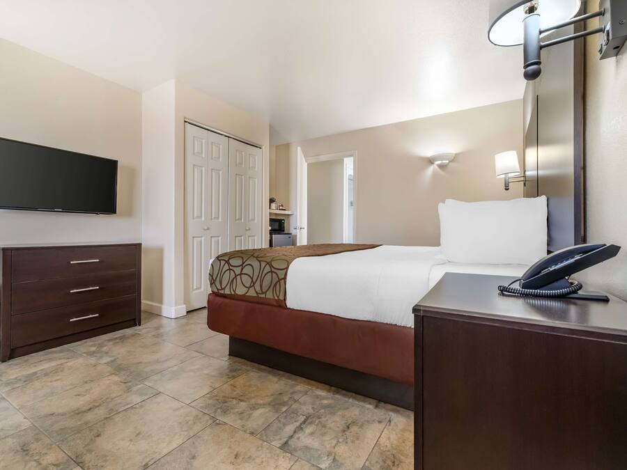 Une chambre d’hôtel comprenant un lit, un bureau avec un téléphone, une télévision et une armoire.