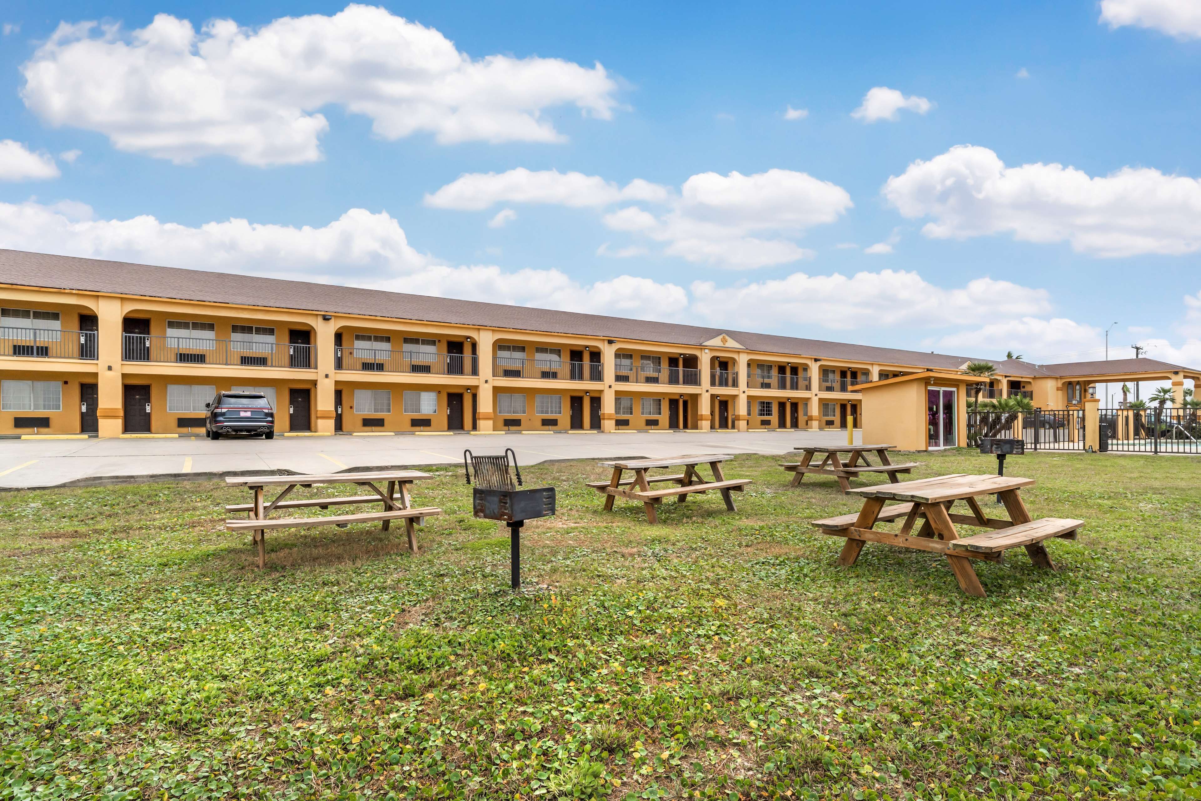A motel with multiple rooms, outdoor picnic tables, and a parking area.