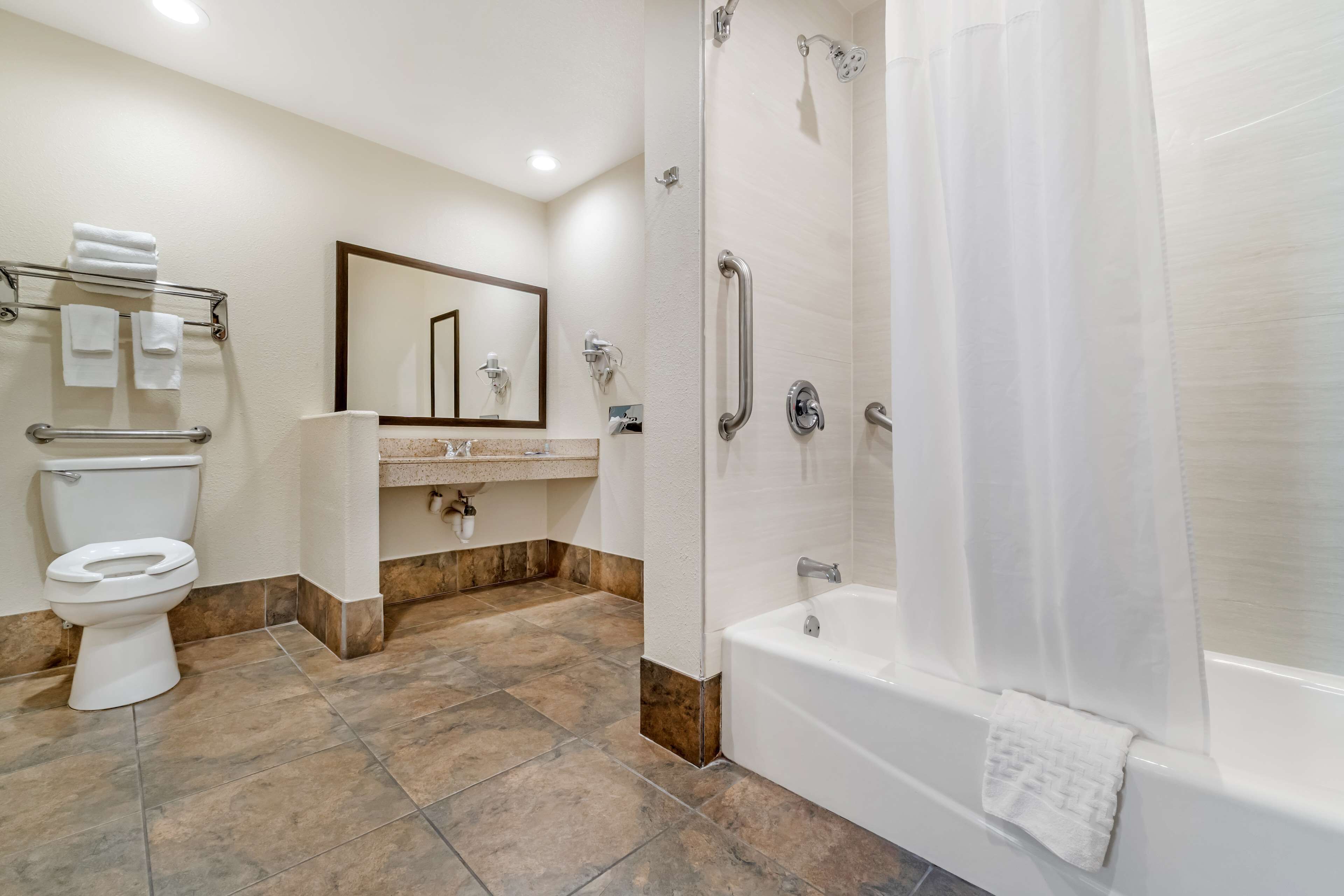 A modern bathroom with a toilet, sink, mirror, shower, and bathtub.