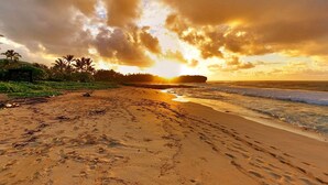 A beach with footprints, palm trees, and a sunset. - Aston at Poipu Kai (Koloa)