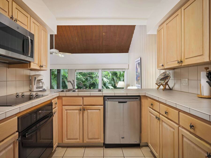 Una cocina moderna con armarios de madera, electrodomésticos de acero inoxidable y vistas al exterior.