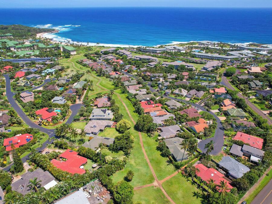 Vue aérienne d’un quartier résidentiel avec des maisons, des routes et une plage.