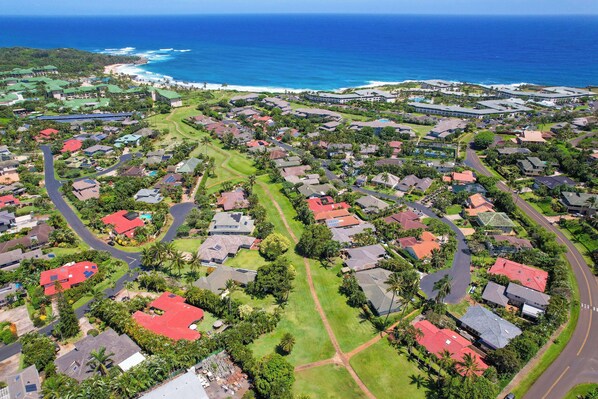 An aerial view of a residential area with houses, roads, and a beach.
