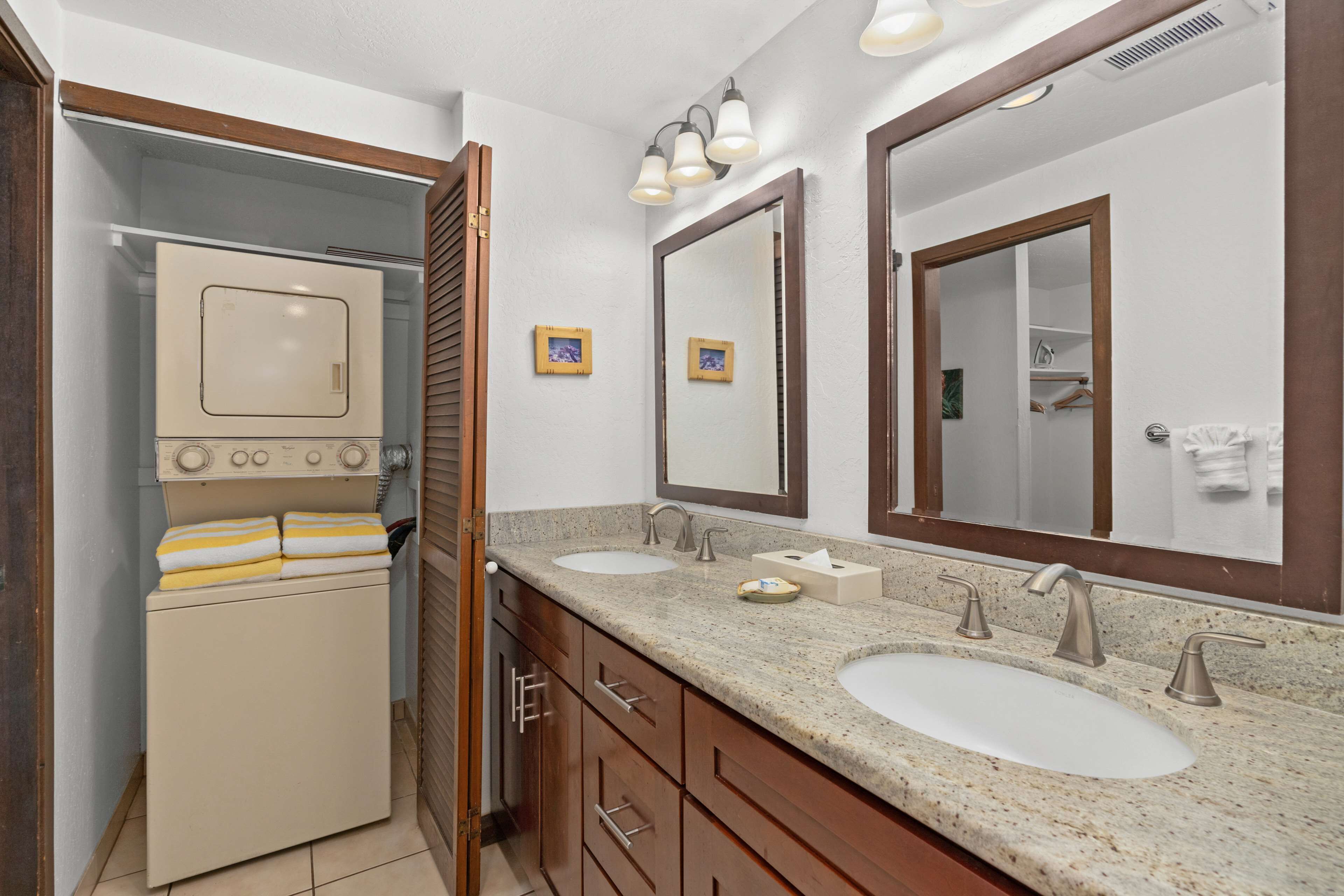 A bathroom with two sinks, a mirror, a towel rack, and a laundry machine.