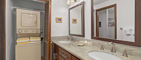 A bathroom with two sinks, a mirror, a towel rack, and a laundry machine.