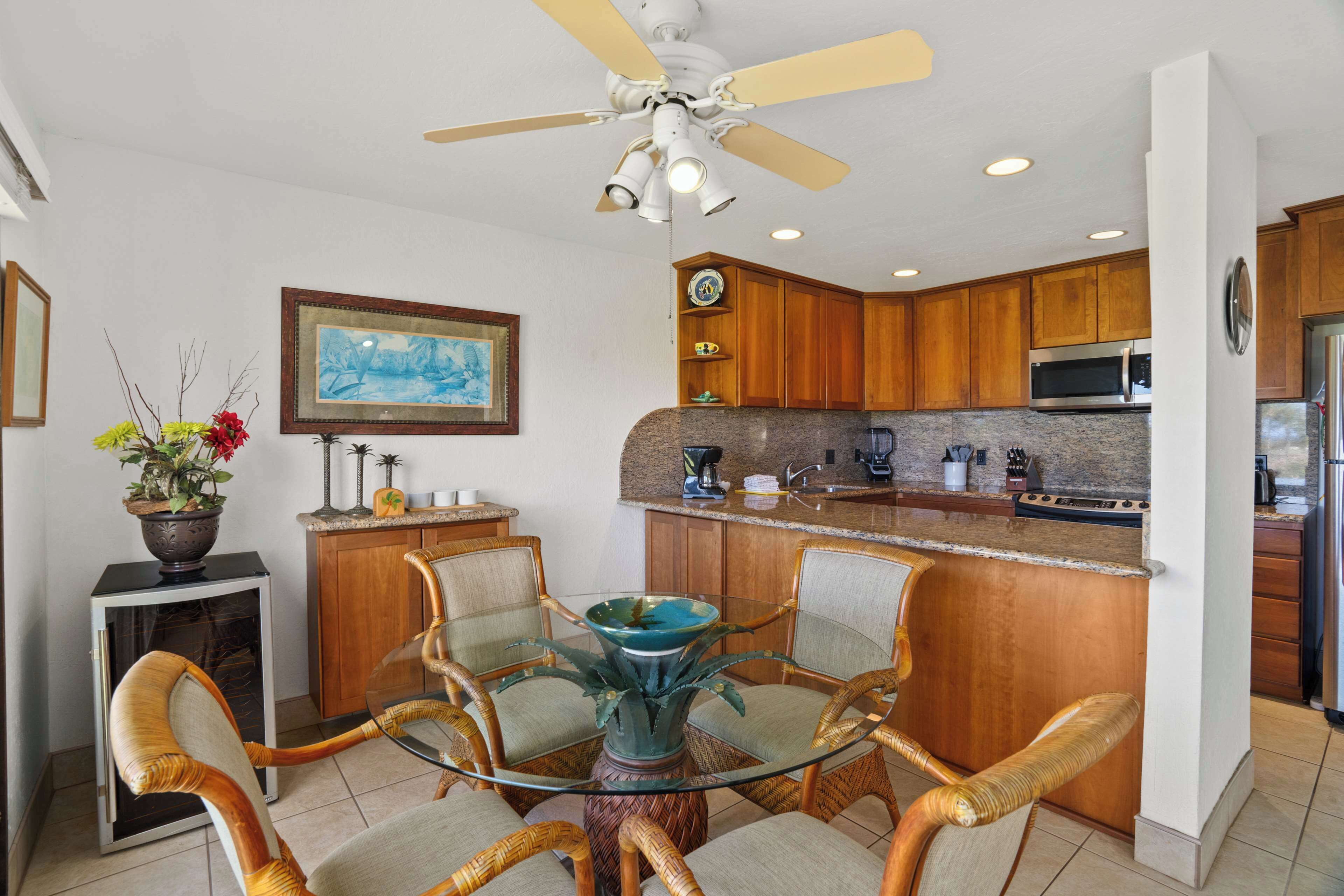 A modern kitchen with wooden cabinets, a granite countertop, a built-in microwave, and a stainless steel refrigerator.