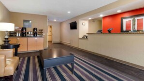 A hotel lobby with a reception desk, a coffee station, a seating area with a sofa and a bench, and a television mounted on the wall. - Extended Stay America Austin Metro (Austin)