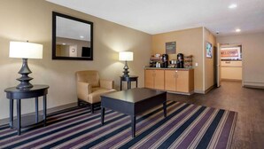 A hotel room with a sofa, two side tables with lamps, a coffee station, and a reception area with a 'Welcome' sign. - Extended Stay America Austin Metro (Austin)