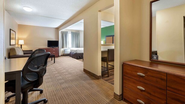 A hotel room with a desk, chair, dresser, and a television. - Extended Stay America Austin Metro (Austin)