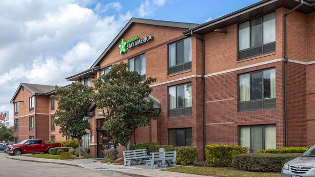 A brick building with a Stay America sign, a red pickup truck, and a silver car parked in front. - Extended Stay America Suites Houston Med Ctr NRG Park Kirby (Houston)