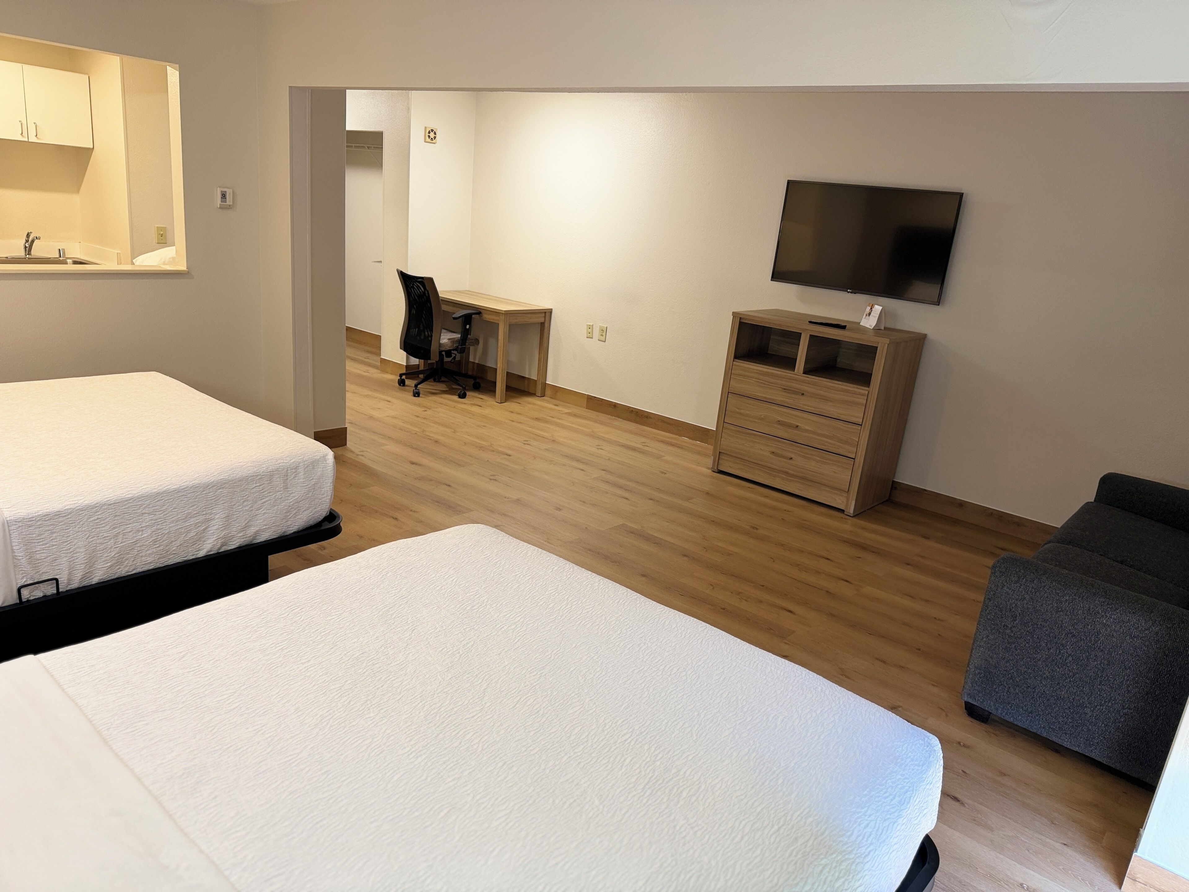 Habitación de hotel con dos camas, un escritorio, una silla, un televisor y un aparador.